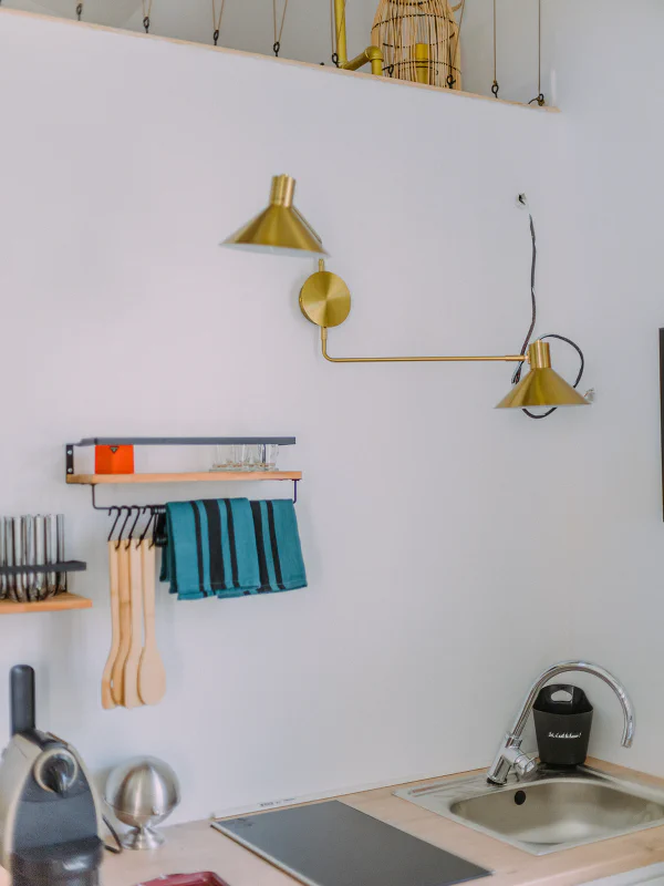 Détail de la kitchenette avec appliques dorées et étagères bois au Château de Laubardemont