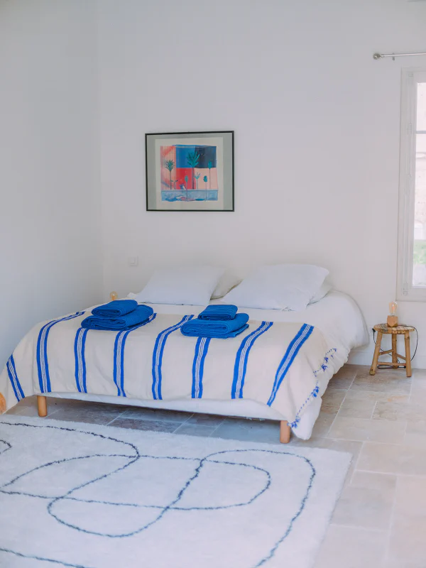 Chambre blanche et bleue avec couverture rayée et serviettes dans le gîte du château