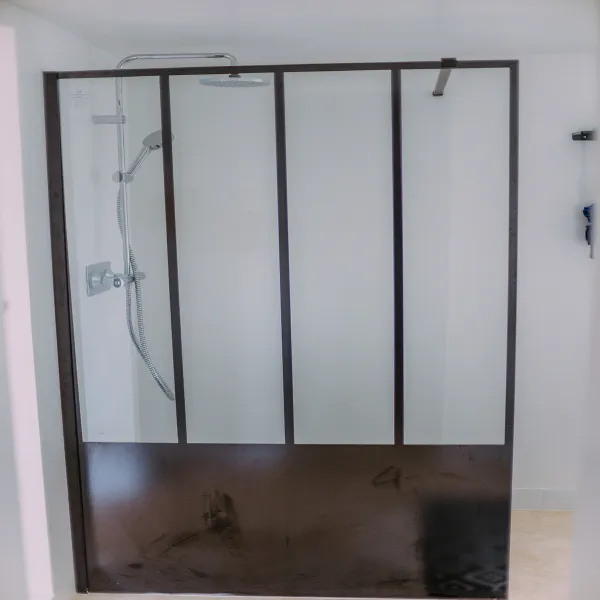 Douche italienne avec verrière noire style atelier dans la salle de bain du gîte