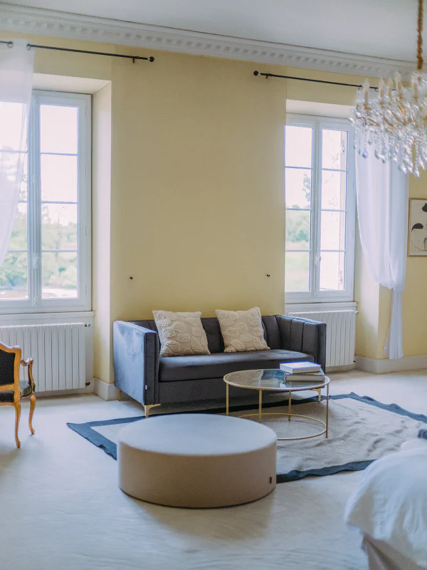 Suite spacieuse avec canapé velours gris et lustre cristal au Château de Laubardemont