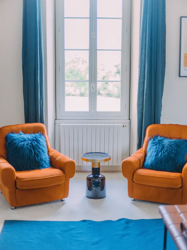 Coin lecture avec deux fauteuils cognac et coussins bleus près de la fenêtre au château