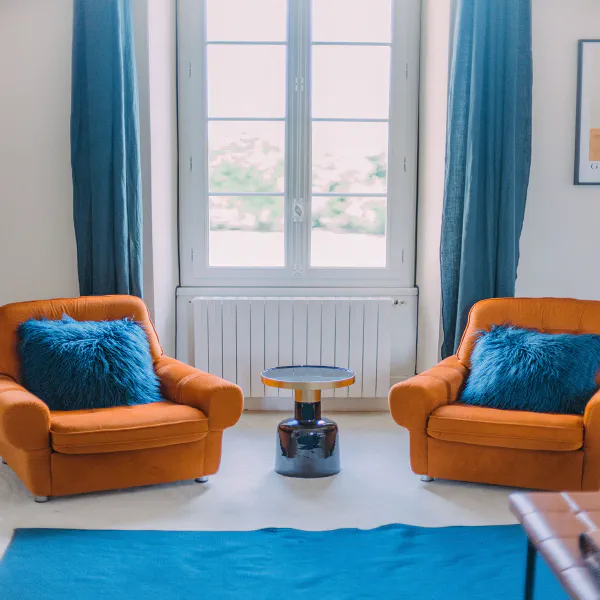 Coin lecture avec deux fauteuils cognac et coussins bleus près de la fenêtre au château