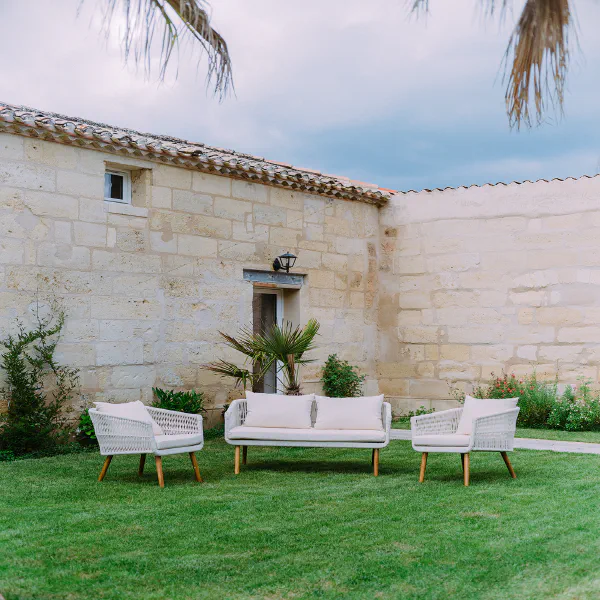 Salon de jardin blanc sur gazon avec façade en pierre du Château de Laubardemont
