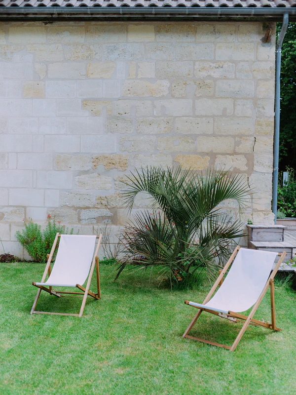 Transats en toile blanche sur pelouse devant les murs en pierre du château