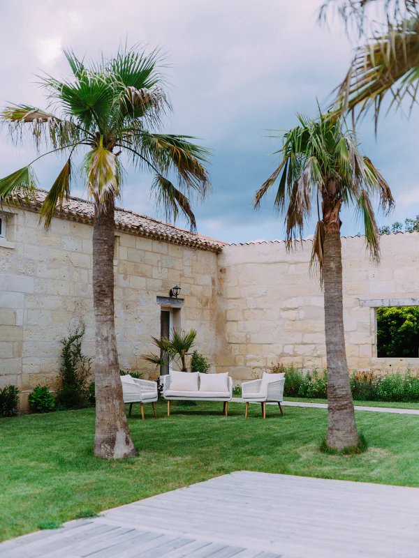Palmiers et salon de jardin avec terrasse en bois au Château de Laubardemont