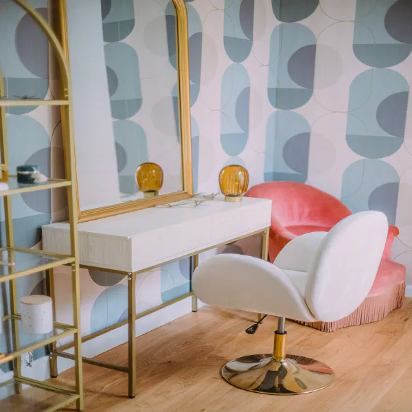 Coin préparation mariée avec fauteuil rose, miroir doré et papier peint pastel au château