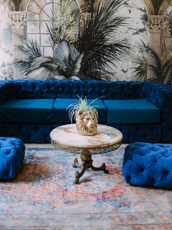 Salon bleu royal avec canapé Chesterfield velours et papier peint tropical au château