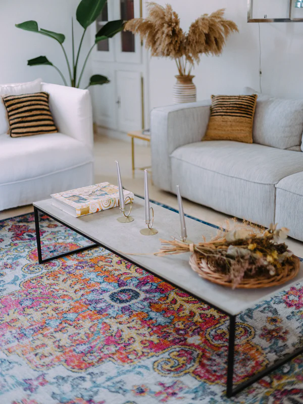 Salon cosy du Château de Laubardemont avec canapé lin, tapis coloré et fleurs séchées