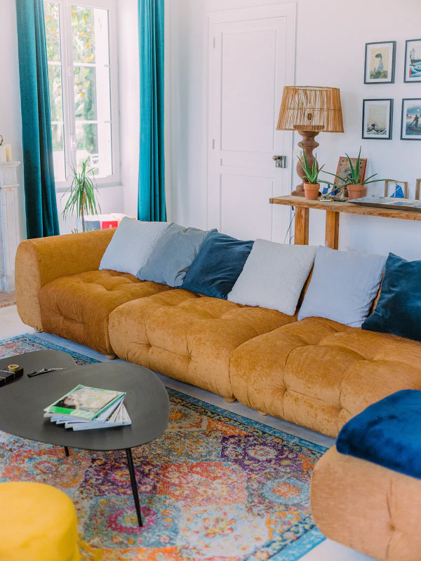 Grand canapé moutarde avec coussins colorés et tapis persan au Château de Laubardemont